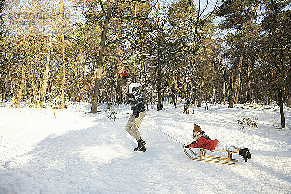 Verspielter Vater mit Söhnen im Schnee im Winter
