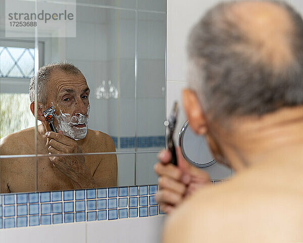 UK  East Sussex  Älterer Mann beim Rasieren vor dem Badezimmerspiegel