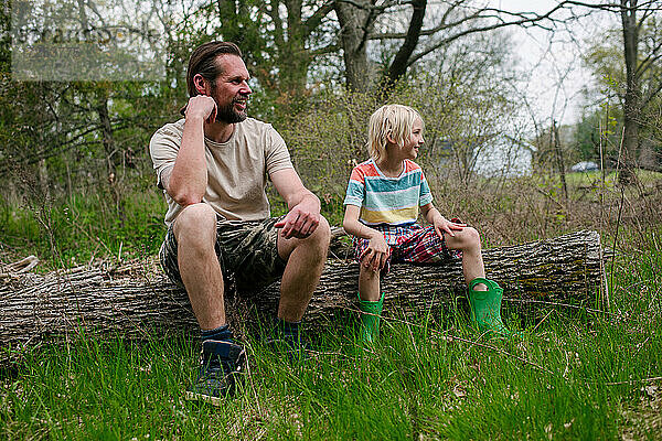 Kanada  Ontario  Kingston  Vater und Sohn sitzen auf einem Baumstamm im Wald