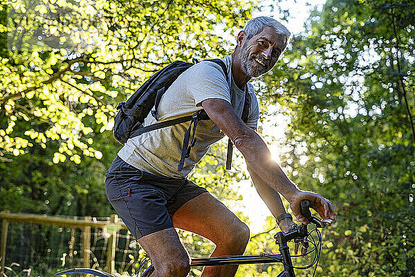 Porträt eines lächelnden reifen Mannes beim Radfahren im Wald