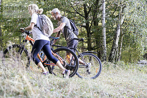 Älteres Paar mit Fahrrädern beim Spaziergang im Wald