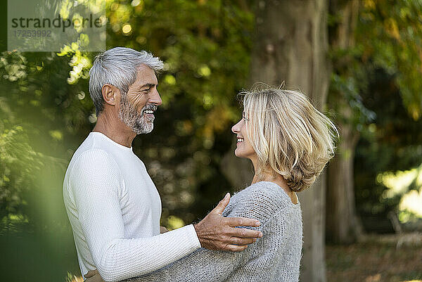 Seitenansicht eines lächelnden reifen Paares  das sich im Hinterhof ansieht