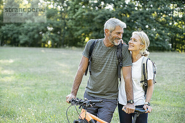 Lächelndes reifes Paar mit Fahrrad schaut sich im Wald an