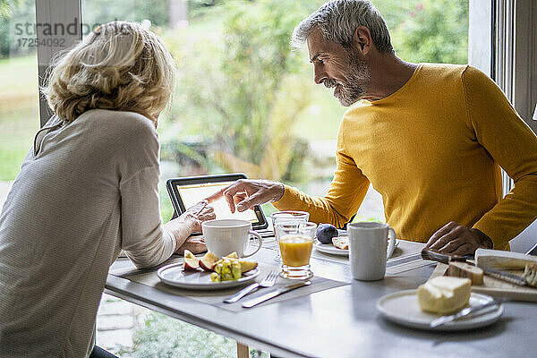 Älteres Paar verwendet digitales Tablet beim Frühstück zu Hause