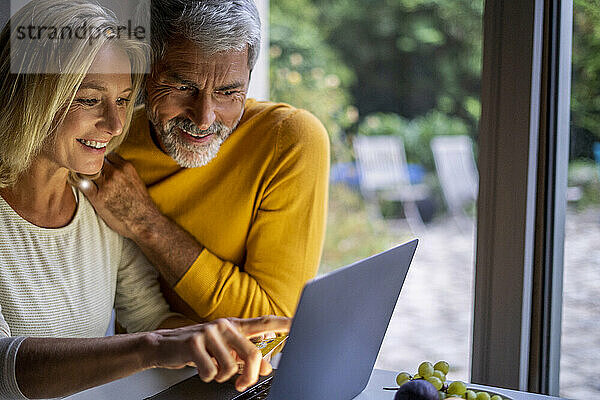 Lächelndes reifes Paar bei der Online-Zahlung mit Kreditkarte
