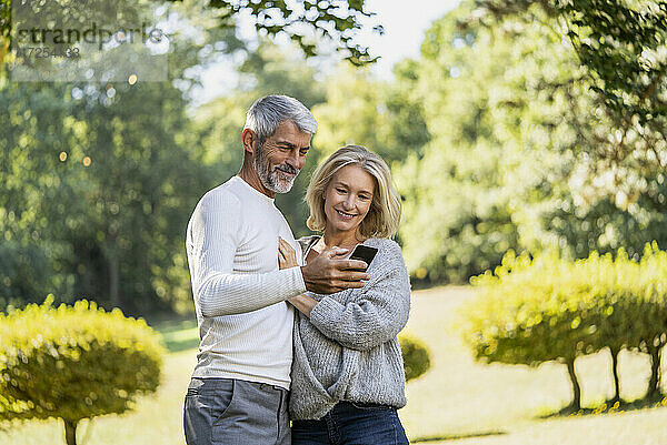 Lächelndes reifes Paar benutzt Smartphone im Hinterhof