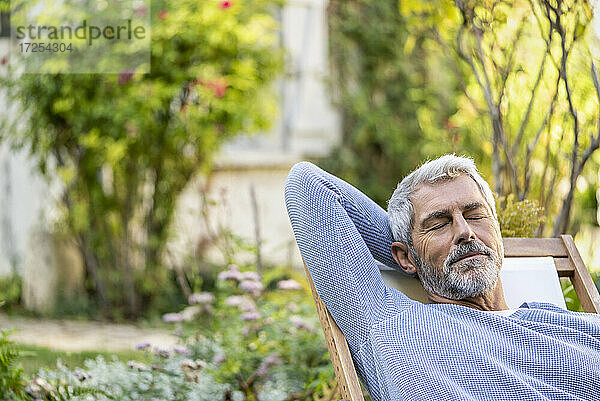 Älterer Mann mit geschlossenen Augen entspannt auf einem Liegestuhl