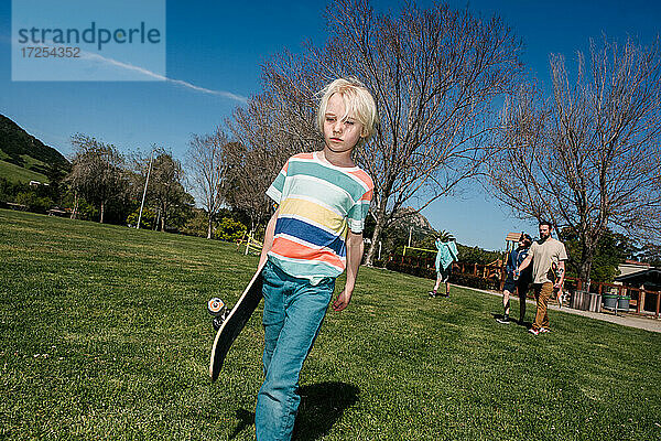 USA  Kalifornien  Big Sur  Junge mit Skateboard zu Fuß im Park