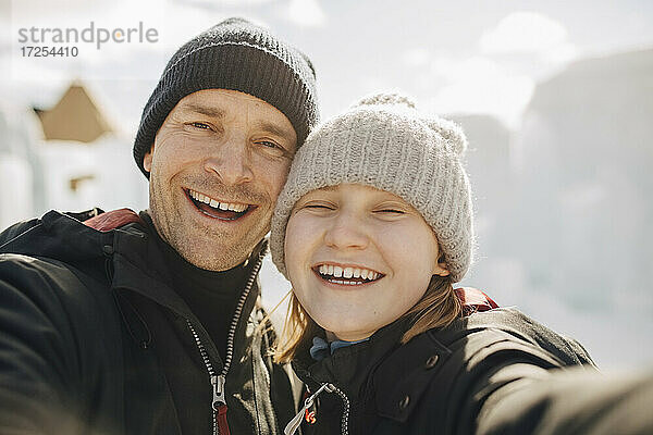 Fröhlicher Vater und Tochter mit Strickmützen im Winter