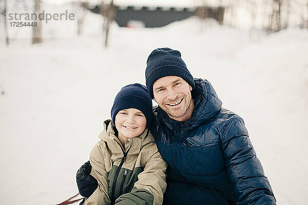 Porträt eines fröhlichen Vaters mit Arm um den Sohn im Winter