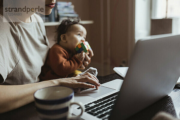 Weibliche Unternehmerin mit Baby Junge arbeiten am Laptop im Büro zu Hause