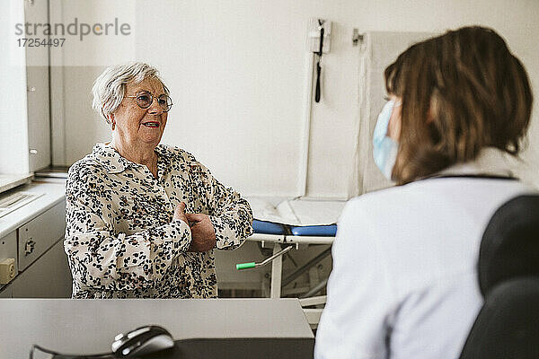 Ältere Patientin im Gespräch mit medizinischem Personal während der Beratung bei COVID-19