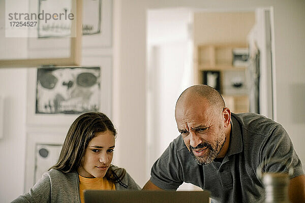 Vater und Tochter mit Laptop in der Küche zu Hause