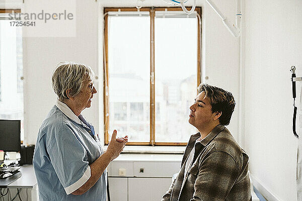 Älterer medizinischer Experte im Gespräch mit einem männlichen Patienten während der Beratung in der Klinik