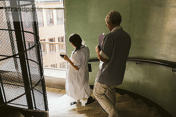 Weiblicher Arzt und Oberschwester bewegen sich die Treppe in der medizinischen Klinik hinunter