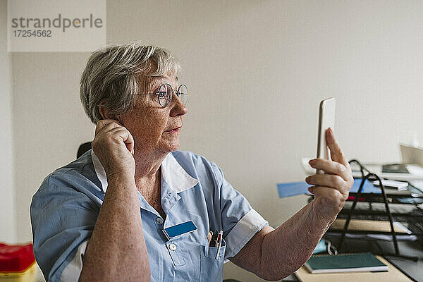 Älteres weibliches Pflegepersonal berät Patienten per Videoanruf in einer medizinischen Klinik