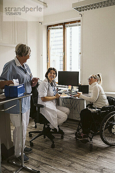 Volle Länge von fröhlichen weiblichen Arzt und behinderte Frau Blick auf ältere Krankenschwester in der medizinischen Klinik