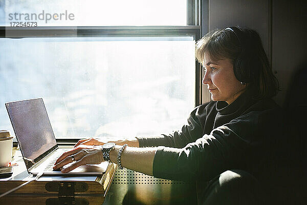 Geschäftsfrau mit Laptop beim Sitzen am Fenster im Zug