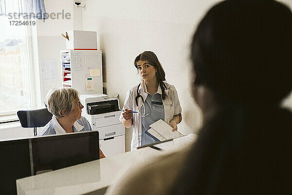 Weiblicher Arzt diskutiert mit älteren Krankenschwester beim Betrachten der Patienten in der medizinischen Klinik