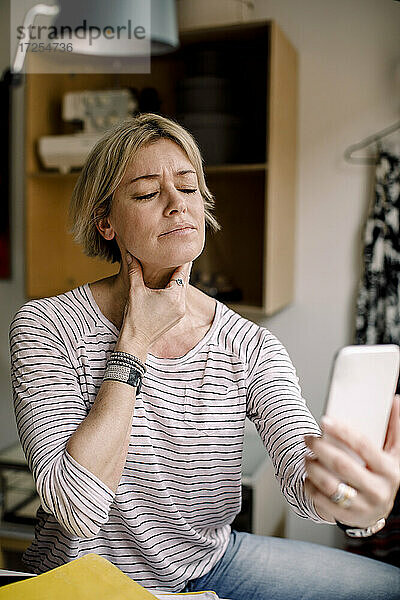 Blonde Frau berät sich mit Arzt über Smartphone zu Hause