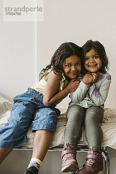 Porträt von lächelnden Mädchen sitzen zusammen auf Untersuchungstisch in der medizinischen Klinik