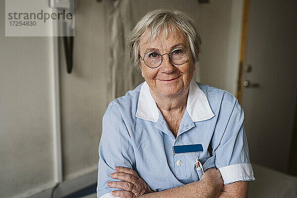 Porträt eines älteren weiblichen medizinischen Experten mit verschränkten Armen