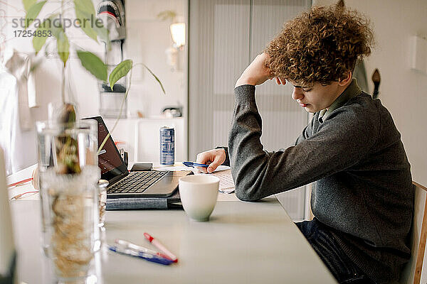 Teenager Junge studiert  während am Tisch sitzen