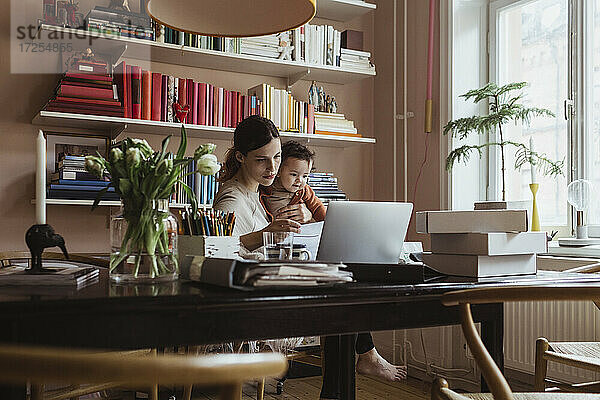 Unternehmerin mit kleinem Sohn arbeitet im Home Office