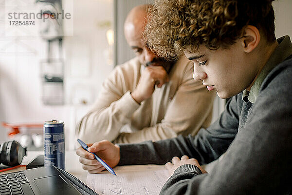 Junge macht Hausaufgaben  während er bei seinem Vater zu Hause sitzt