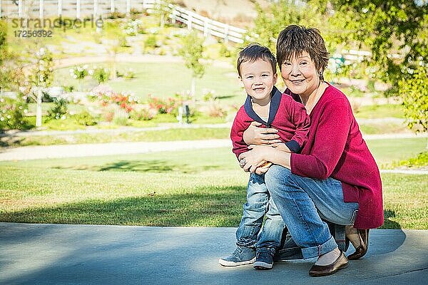 Glückliche chinesische Großmutter hat Spaß mit ihrem gemischtrassigen Enkel draußen