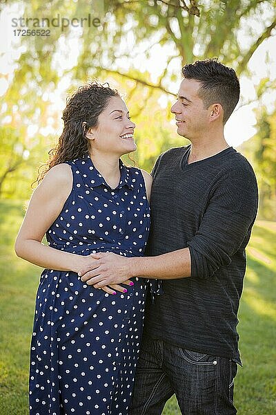 Glücklicher hispanischer Mann mit seiner schwangeren Frau im Freien im Park