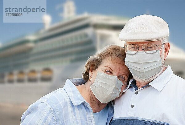 Älteres Paar mit Gesichtsmasken vor einem Passagier-Kreuzfahrtschiff stehend
