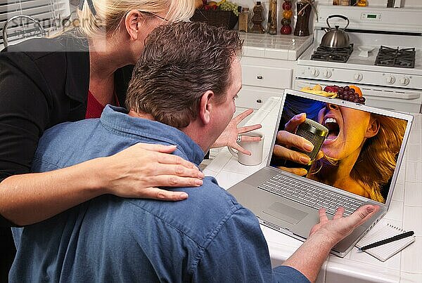 Ehepaar in der Küche mit Laptop mit singender Frau auf dem Bildschirm