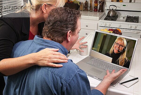 Paar in der Küche mit Laptop mit Kundenbetreuerin auf dem Bildschirm
