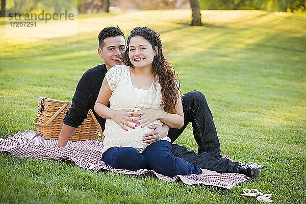 Friedliches schwangeres hispanisches Paar im Park im Freien