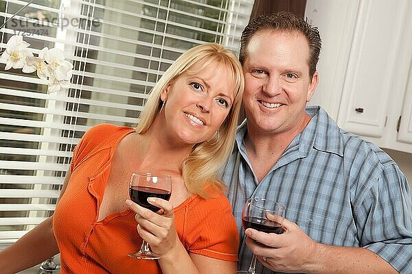 Glückliches Paar  das ein Glas Wein in der Küche genießt