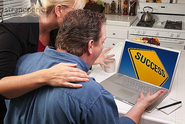 Ehepaar in der Küche mit Laptop mit gelben Erfolg Straßenschild auf dem Bildschirm