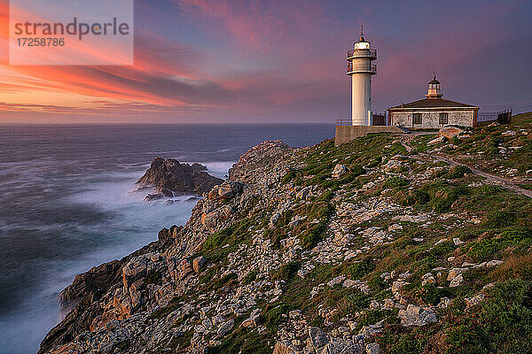 Meer Landschaft Blick auf Cape Tourinan Leuchtturm bei Sonnenuntergang mit rosa Wolken  Galicien  Spanien  Europa