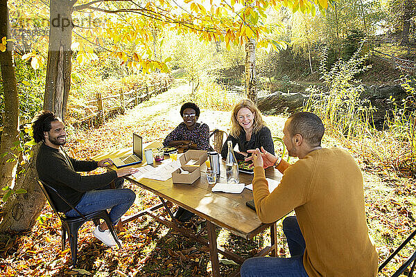 Geschäftsleute treffen und essen am Tisch im sonnigen Herbst Park