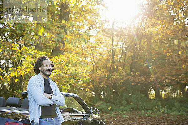 Glücklicher Mann am Cabrio im sonnigen Herbst Park