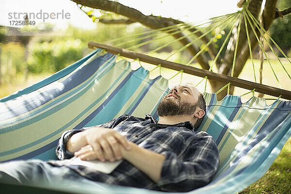 Serene Mann entspannt in sonnigen Sommer Hängematte