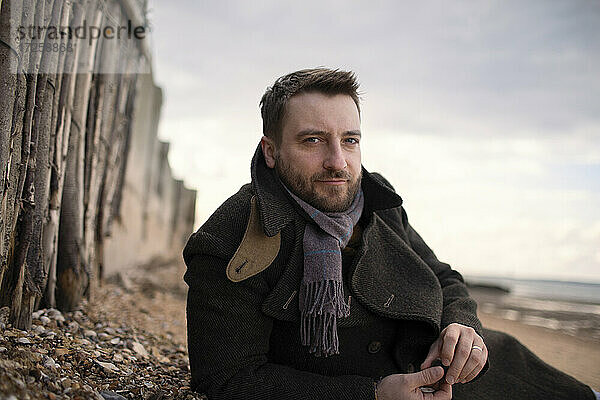 Porträt selbstbewusst gut aussehend Mann im Wintermantel am Strand
