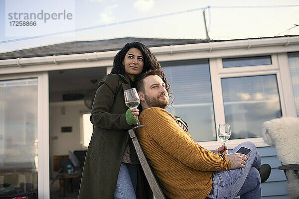 Glückliches Paar entspannt mit Weißwein auf der Terrasse
