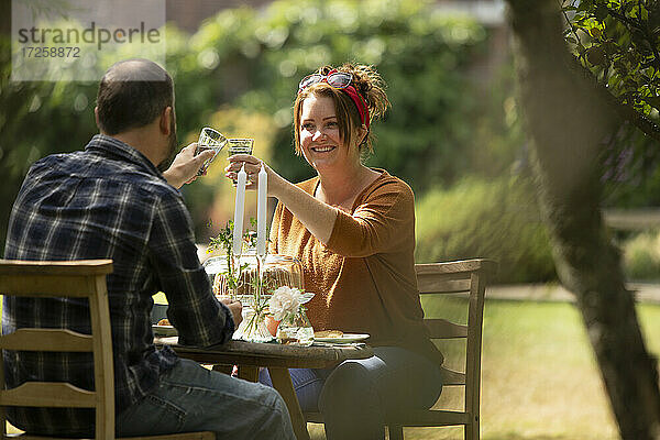Glückliches Paar  das sich am sonnigen Gartentisch bindet
