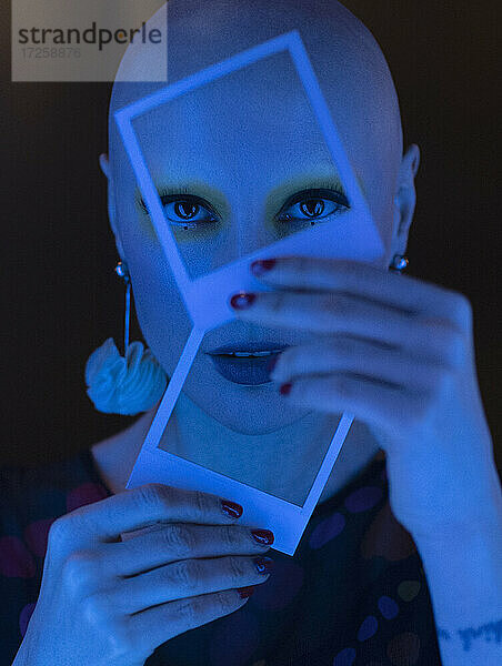 Close up Porträt stilvolle Frau mit rasiertem Kopf hält Polaroids