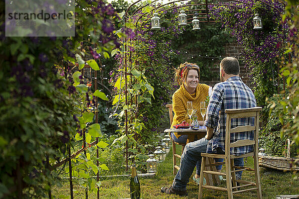 Glückliches Paar genießt Champagner im idyllischen Sommergarten