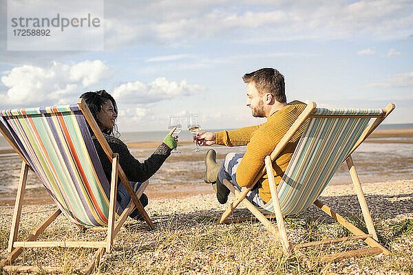 Glückliches Paar Toasting Weingläser auf sonnigen Winter Strand