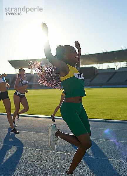 Glückliche weibliche Leichtathletin gewinnt Rennen auf sonniger Strecke