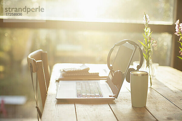 Kopfhörer  Laptop und Kaffee auf dem sonnigen Cafe-Tisch