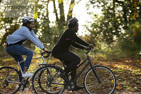 Freunde fahren Fahrräder durch Herbstblätter im Park